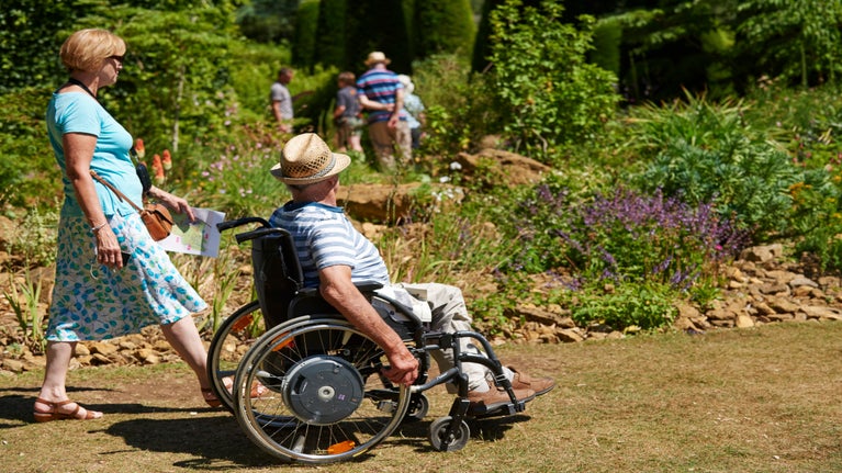 a visitor in a wheelchair enjoys the gardens at Hidcote